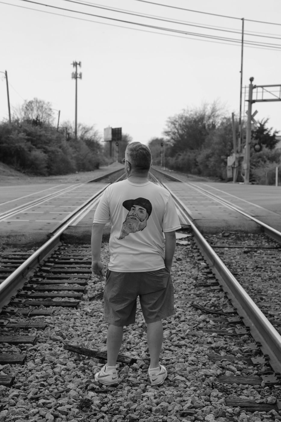 Mighty Rock standing between railroad tracks, seen from behind